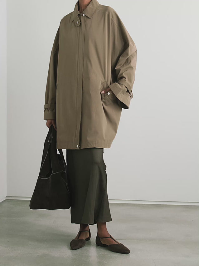 This organic cotton trench coat from TOTEME elevates any outfit with its clean, structured silhouette. Crafted from crisp organic cotton, it offers comfort and sustainability. Its roomy shape ensures ease of movement, while cuff tabs and a throat latch beneath the collar add thoughtful detailing. The partially concealed placket creates a sleek, polished look, making this coat a versatile essential for refined style.