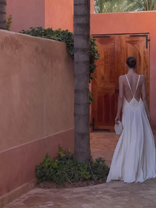 Effortlessly graceful, the Lavinia Dress by Arcina Ori captures modern elegance with a plunging V-neckline adorned with delicate lace detailing. Adjustable straps converge at an open back for a striking silhouette, while the softly ruched skirt flows with fluid movement. Crafted from lightweight georgette, this gown offers comfort and sophistication for intimate celebrations or romantic occasions.